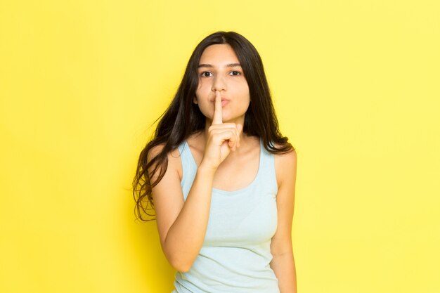 A front view young female in blue shirt posing with silence sign