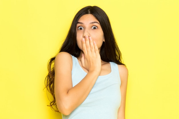 A front view young female in blue shirt posing with surprised expression