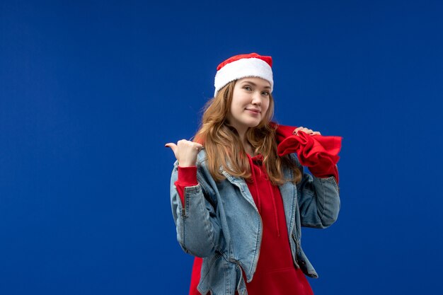 Front view young female carrying bag full of presents on blue space