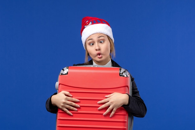 Front view young female carrying heavy red bag on a blue wall vacation woman holiday