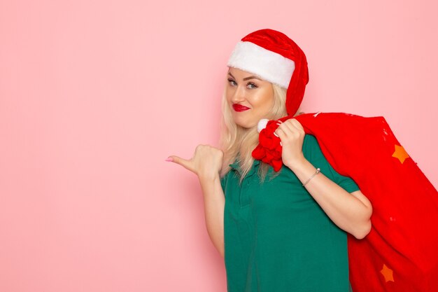 front view young female carrying red bag with presents on pink wall holiday model new year color photo santa