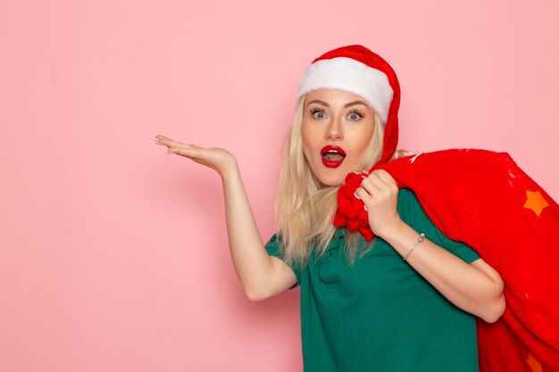 front view young female carrying red bag with presents on pink wall holidays model xmas new year color photo santa