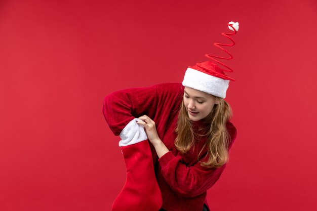 Вид спереди молодая женщина проверяет рождественский носок, красный праздник Рождества