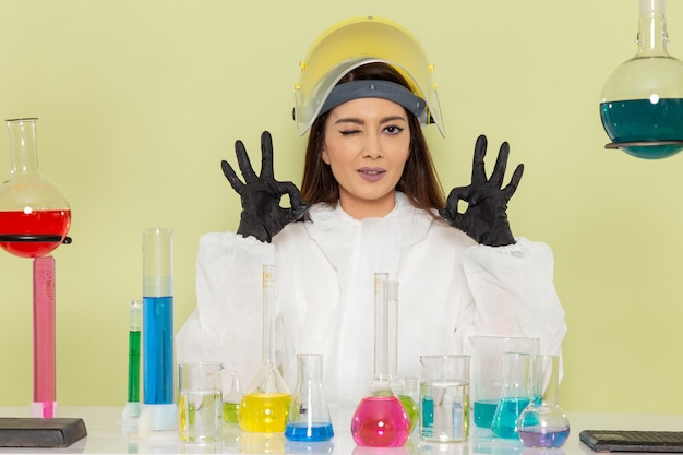 무료 사진 밝은 녹색 벽 화학 물질 화학 직업 과학 실험실에서 솔루션으로 작업하는 특수 보호 복에 전면보기 젊은 여성 화학자