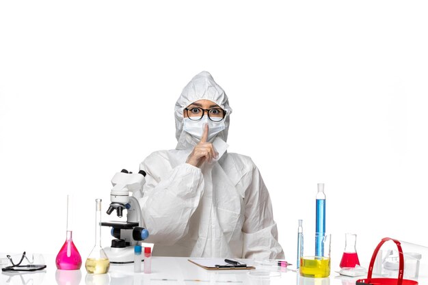 Front view young female chemist in special protective suit asking to be silent on white background virus lab covid- chemistry