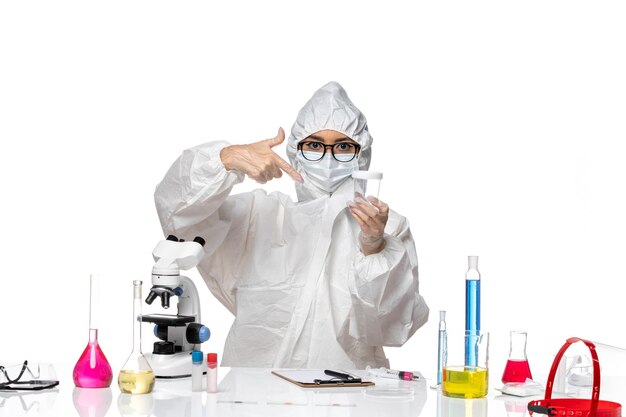 Вид спереди молодая женщина-химик в специальном защитном костюме, держащая пустую колбу на белом фоне, лабораторный вирус ковид-химии