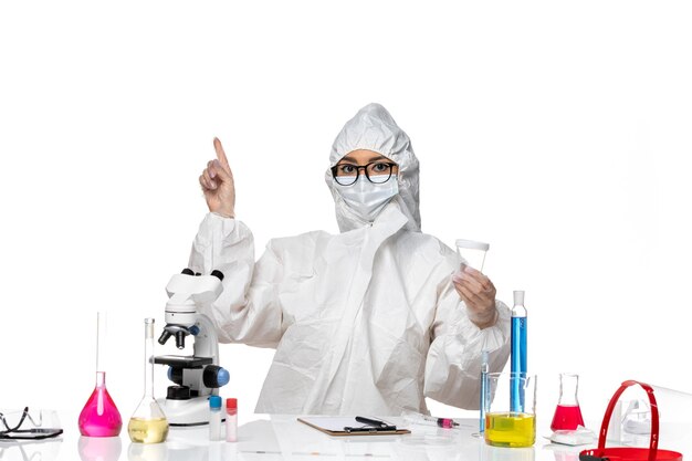 Front view young female chemist in special protective suit holding empty flask on white desk lab covid- chemistry virus