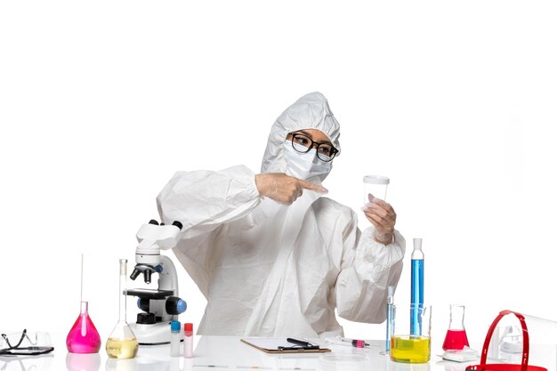 Front view young female chemist in special protective suit holding empty flask on white floor lab covid- chemistry virus health