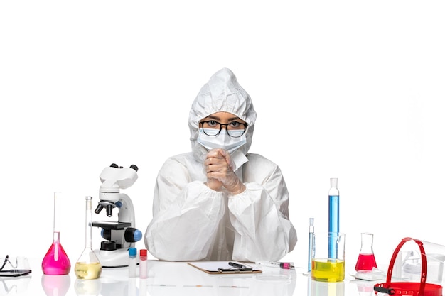 Вид спереди молодая женщина-химик в специальном защитном костюме, просто сидящая на белом фоне, лаборатория здоровья вируса химии ковид