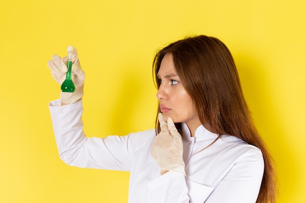 Vista frontale di giovane chimico femminile in vestito bianco che tiene soluzione chimica