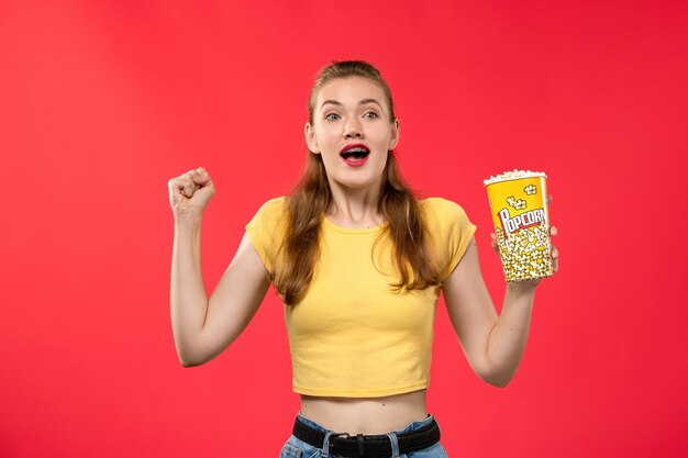 팝콘 패키지를 들고 붉은 벽 영화 극장 시네마 여성 재미있는 영화에 기뻐하는 영화관에서 전면보기 젊은 여성