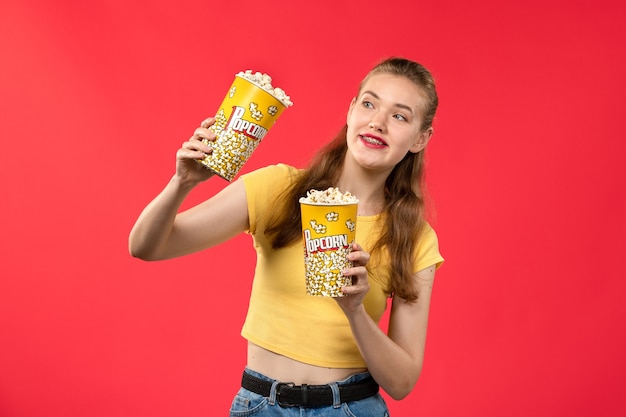 밝은 빨간색 벽 영화관 영화관 여성 재미있는 영화에 팝콘 패키지를 들고 영화관에서 전면보기 젊은 여성