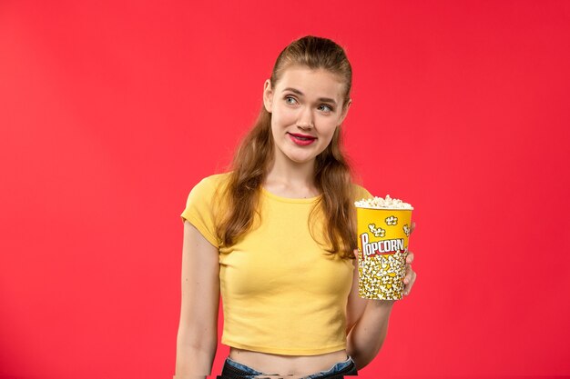 Front view young female at cinema holding popcorn on red wall movie theater cinema female color fun time film