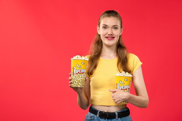 팝콘을 들고 붉은 벽에 웃고있는 영화관에서 전면보기 젊은 여성 영화관 영화관 여성 재미있는 영화