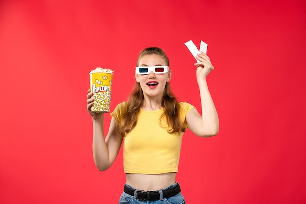 Front view young female at cinema holding popcorn and tickets on the red wall movie theater cinema female colors