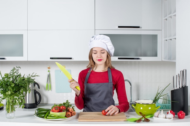Front view young female cook in apron chopping tomato stock photo
