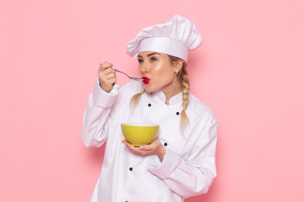 Front view young female cook in white cook suit posing holding green plate on the pink space cook cuisine job work  photo