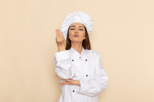 白い壁に白いクックスーツで若い女性料理人の正面図