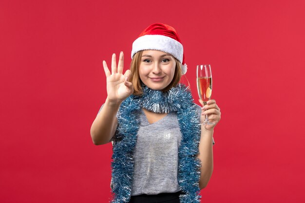 Front view young female counting showing number on red wall color christmas holiday