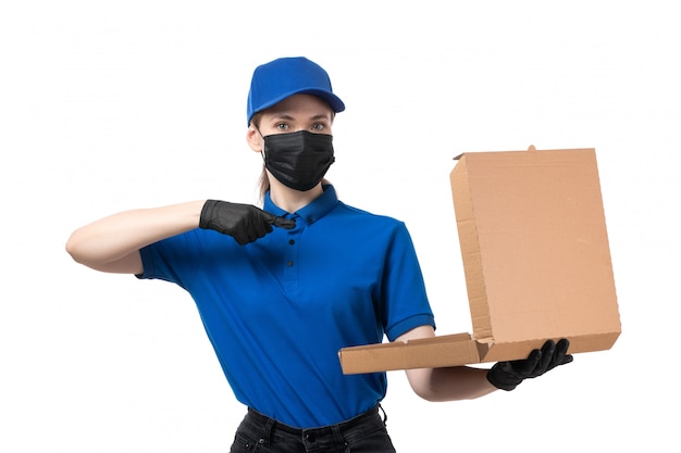 Free photo a front view young female courier in blue uniform black gloves and black mask holding food delivery package