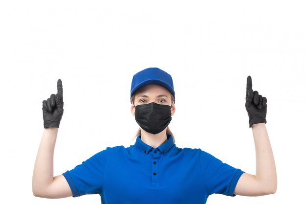 A front view young female courier in blue uniform black gloves and black mask posing