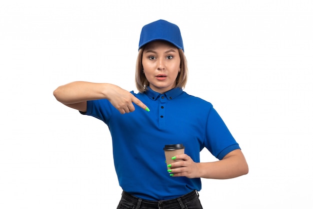 A front view young female courier in blue uniform holding coffee cup