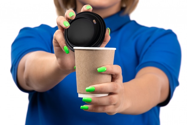 Молодая женщина-курьер в синей форме, держащая чашку кофе, вид спереди