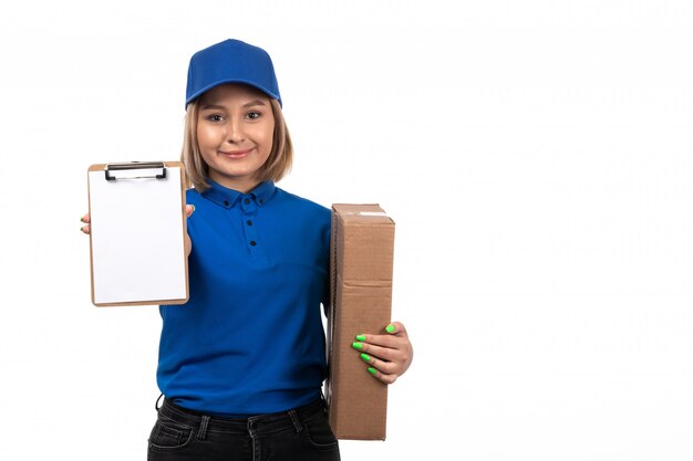 A front view young female courier in blue uniform holding food delivery package and notepad for signatures