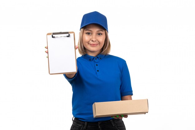 フードデリバリーパッケージと署名用のメモ帳を保持している青い制服を着た正面の若い女性宅配便