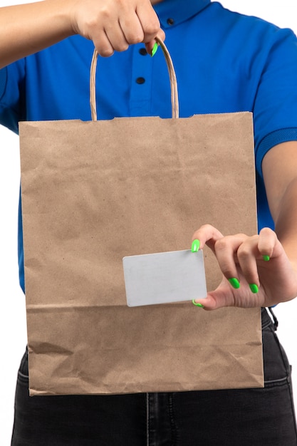 Free photo a front view young female courier in blue uniform holding food delivery package and white card