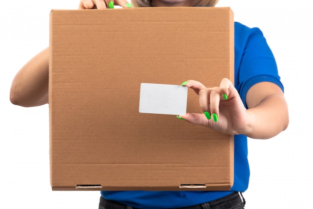 A front view young female courier in blue uniform holding food delivery package and white card