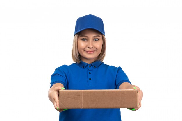 A front view young female courier in blue uniform holding food delivery package with smile on her face