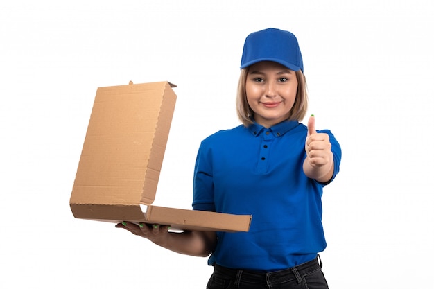 A front view young female courier in blue uniform holding food delivery package with smile on her face