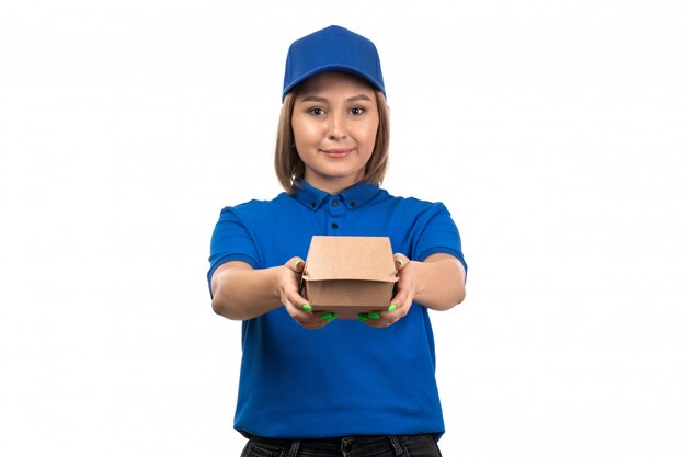 Молодая женщина-курьер в синей форме, держащая пакет для доставки еды, вид спереди