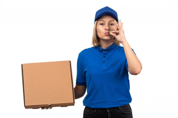 A front view young female courier in blue uniform holding food delivery package