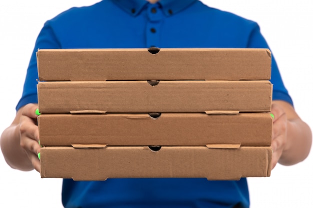 A front view young female courier in blue uniform holding food delivery packages with smile