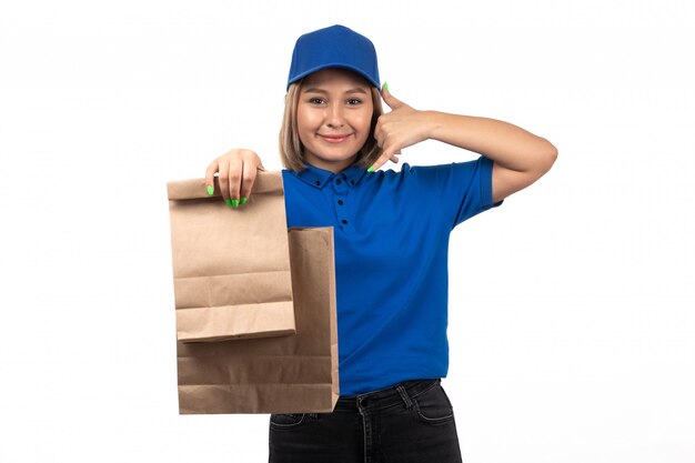 A front view young female courier in blue uniform holding food delivery packages