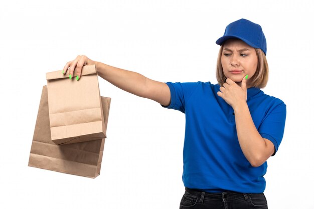 A front view young female courier in blue uniform holding food delivery packages