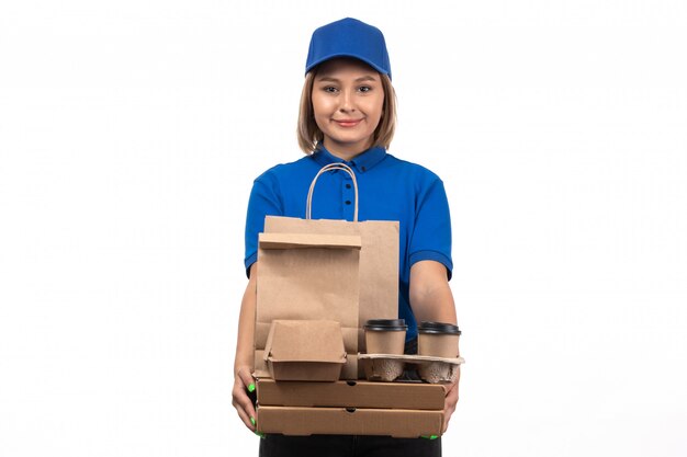 Молодая женщина-курьер в синей форме, держащая пакеты с доставкой еды, вид спереди