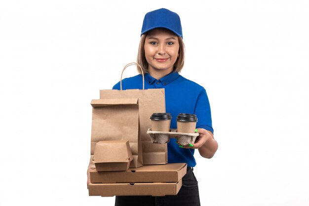 A front view young female courier in blue uniform holding food delivery packages