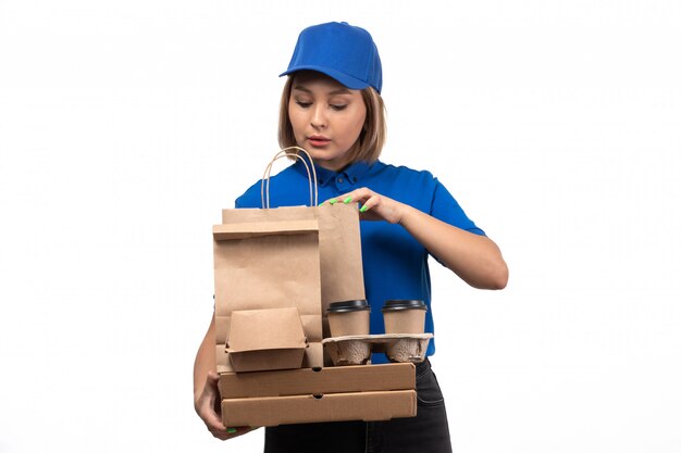 A front view young female courier in blue uniform holding food delivery packages