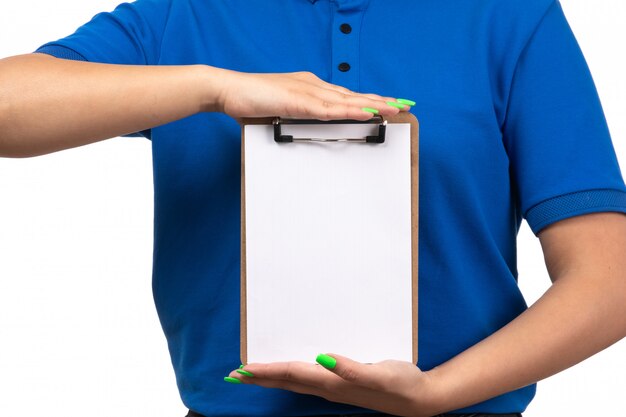 A front view young female courier in blue uniform holding notepad for signatures