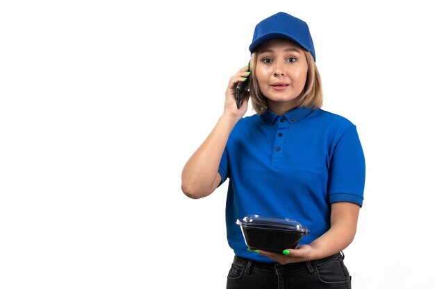 携帯電話と食物と一緒にボウルを保持している青い制服を着た正面若い女性宅配便