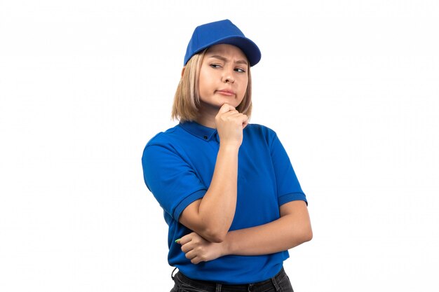 A front view young female courier in blue uniform just posing with thinking expression