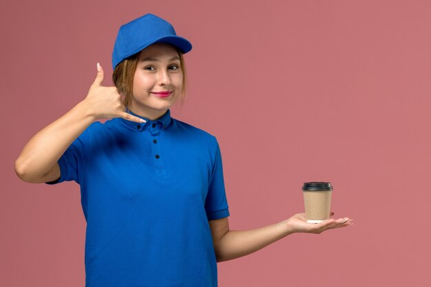 커피, 서비스 균일 한 배달 여자의 배달 컵을 들고 포즈 파란색 유니폼에 전면보기 젊은 여성 택배