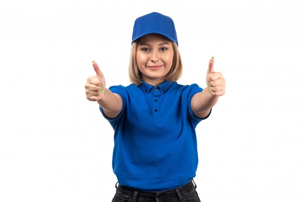 A front view young female courier in blue uniform posing and showing like signs