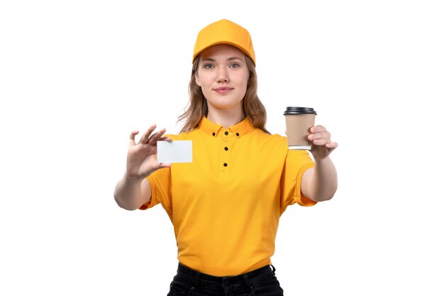 A front view young female courier female worker of food delivery service holding coffee cup with white card and smiling on white