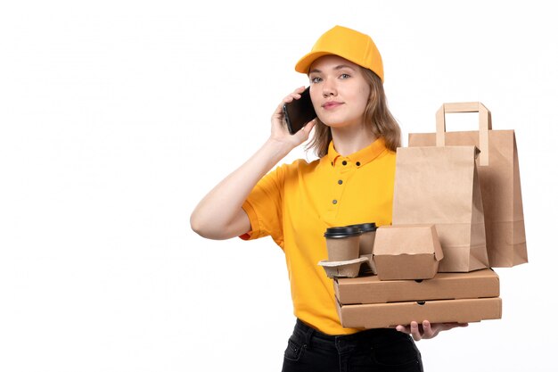 白の電話で話しながらコーヒーカップの食品パッケージを保持している食品配達サービスの正面の若い女性宅配便女性労働者