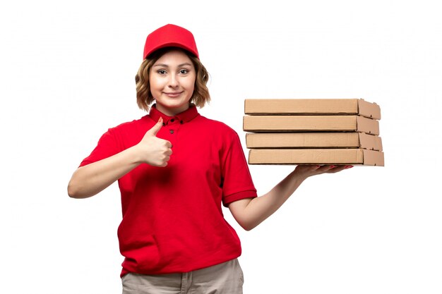 A front view young female courier female worker of food delivery service holding food delivery boxes smiling on white