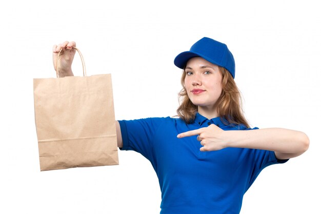 A front view young female courier female worker of food delivery service holding food delivery package smiling on white